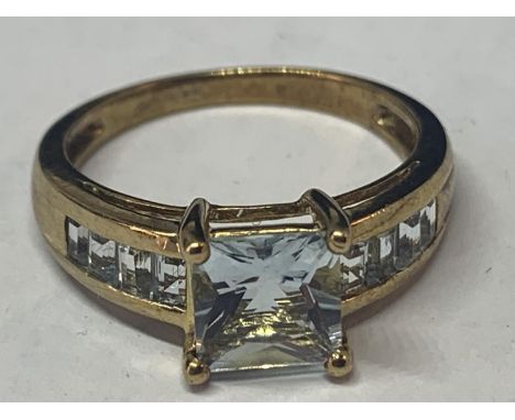 A 9 CARAT GOLD RING MARKED 375 WITH A LARGE CENTRAL PALE BLUE SQUARE STONE AND FOUR MATCHING STONES ON EACH SHOULDER SIZE Q G
