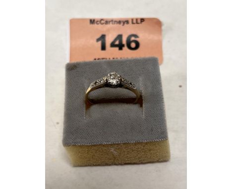 A diamond solitaire ring with two small stones to each shoulder. In gold but unmarked. 1g gross. Size K