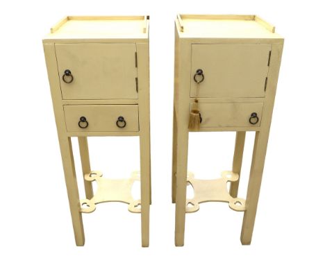 A pair of modern bedside cabinets, painted cream, each with a single door and drawer below with ring handles, lower tier shel