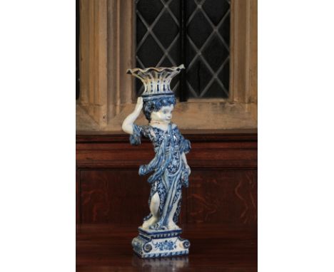 A DUTCH DELFTWARE BLUE AND WHITE VASE late 17th/early 18th century, modelled as a young girl wearing a floral dress carrying 