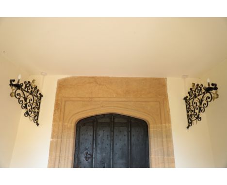 A PAIR OF WROUGHT IRON LAMP BRACKETS 17th century or later, painted in black and gold, the scrolling design with spiraling le