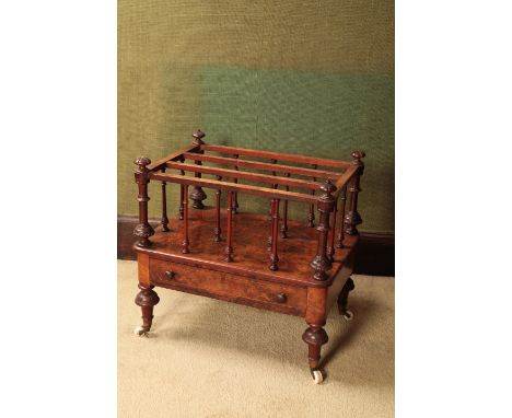 A VICTORIAN BURR WALNUT CANTERBURYwith turned uprights and a single drawer, on turned and carved legs ending in ceramic casto