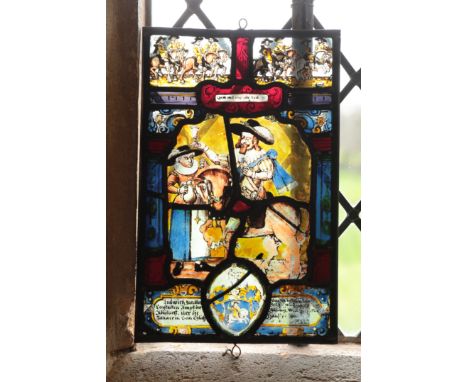 A SWISS STAINED GLASS PANEL with a soldier on horseback beside a lady holding a flagon above a coat of arms and inscription: 