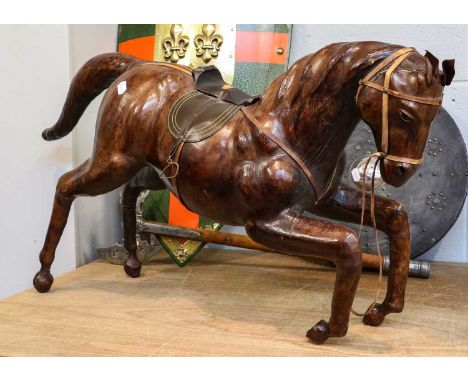 A leather horse with bridle and saddle, approximately 100cm long, together with two reproduction decorative shields and a sim