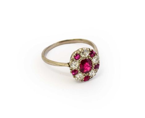 A synthetic ruby and diamond cluster ring, the oval synthetic ruby within a border of round brilliant cut diamonds alternatin