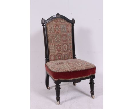 A Victorian ebonised mahogany aesthetic movement nursing chair. Raised on turned supports with fabulous tapestry upholstered 