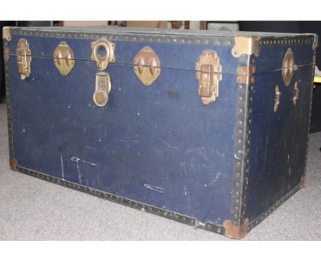 A vintage large steamer trunk with hinged top and clasps to front having brass bound corners etc
