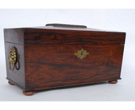 A Georgian rosewood tea caddy box of sarcophagus form having brass lion mask handles to the sides with appointed interior set