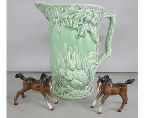 A ceramic Wade jug in mint green decorated in relief with forest scene, together with two Beswick foals.  **PLEASE NOTE THIS 
