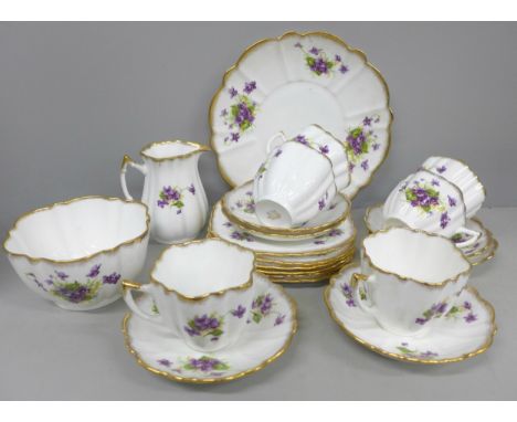 A bone china tea set having purple violet design and gilt detailing, six teacups, six saucers, six side plates, cake serving 