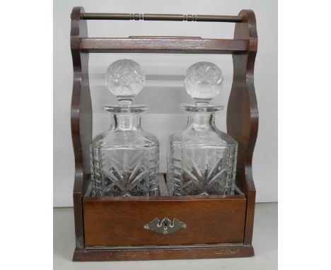 A mahogany tantalus with two crystal cut glass decanters. No key.  **PLEASE NOTE THIS LOT IS NOT AVAILABLE FOR PACKING AND PO