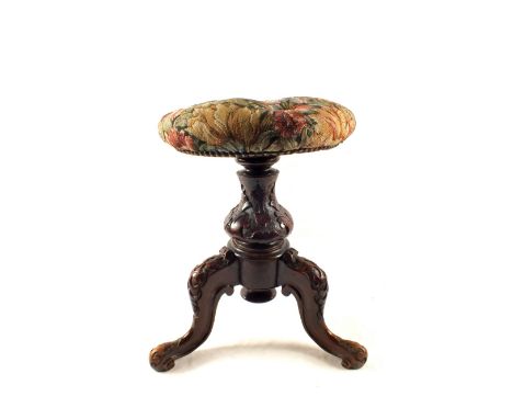 A Victorian carved Mahogany circular revolving piano stool on tripod legs