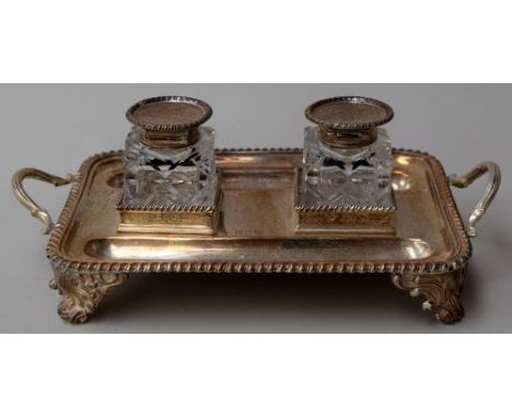 A Victorian inkwell set, the two cut glass inkwells with silver tops on a silver tray raised on floral paw feet, Thomas Bradb