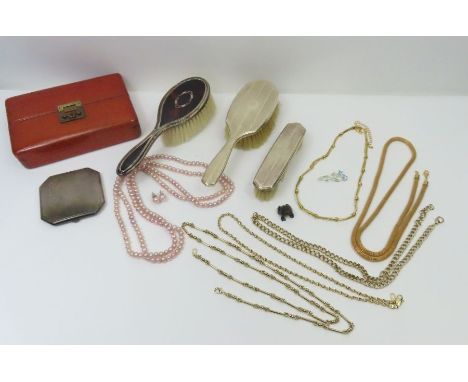 A collection of costume jewellery in a leather case, along with three silver backed hairbrushes and silver engine turned comp