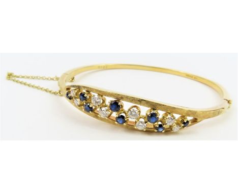 An 18ct gold sapphire and diamond hinged bangle, the front of the with alternating claw set stones in a cut out mount with te