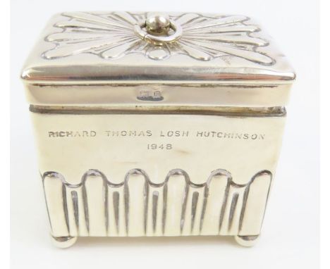 A 20th century sterling silver tea caddy, with a hinged lid and embossed decoration with a loop ring and standing on four bun