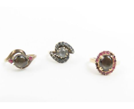 A black star sapphire and ruby ring; a black star sapphire and sapphire ring; and a black star sapphire and ruby cluster ring