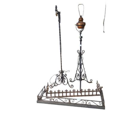 An oil lamp on a wrought iron stand, a wrought iron standard lamp and two fire kerbs