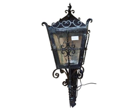 A black painted wrought iron wall lantern with bracket, 74cms high max