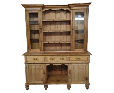 A Victorian pine kitchen dresser the upper section having central shelves with metal cup hooks, flanked by glazed doors enclo