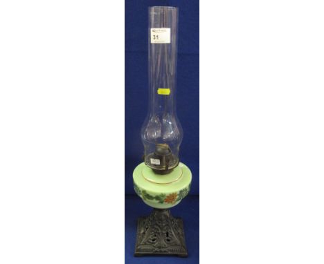 Early 20th Century brass single burner oil lamp with ceramic floral painted reservoir and cast metal base with clear chimney.