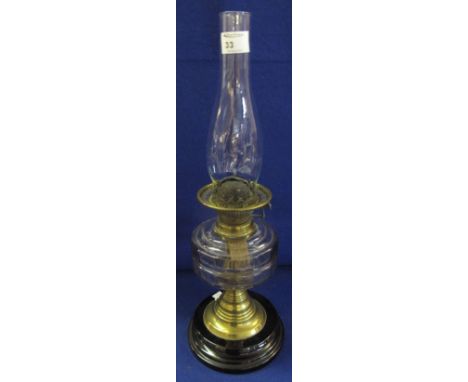 Early 20th Century brass double burner oil lamp with glass reservoir, brass pedestal and ceramic base with clear chimney.