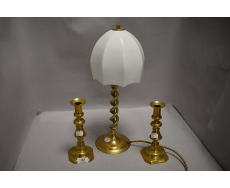 An Edwardian twist stem brass lamp having milk glass shade along with two candle sticks