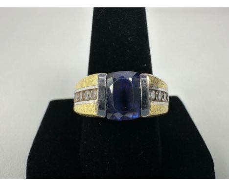 22-24KT tested white and yellow gold size 10.5 ring. The center stone is tanzanite, measuring approximately 6.58 x 9.82 mm, a