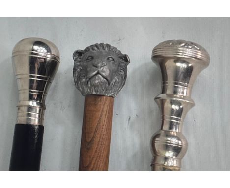 Two of the walking sticks are black wood with silver handles and silver tips. The last walking stick is brown wood with a sil