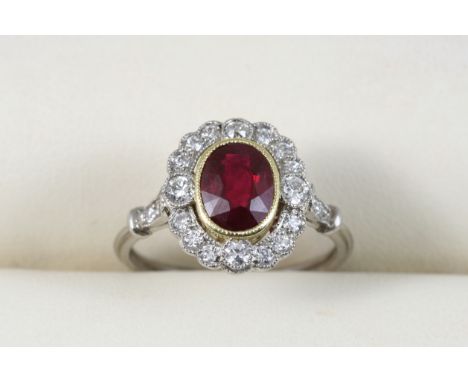 A RUBY AND DIAMOND CLUSTER RING the oval-shaped ruby is set within a surround of circular-cut diamonds, with two diamonds set