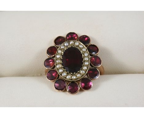 A GEORGIAN GARNET AND PEARL CLUSTER RING the oval-shaped flat cut garnet is set within a surround of small pearls and an oute