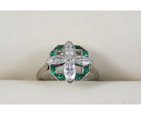 AN EMERALD AND DIAMOND FLOWER HEAD RING centred with four marquise-cut diamonds within a surround of calibre-cut emeralds, in