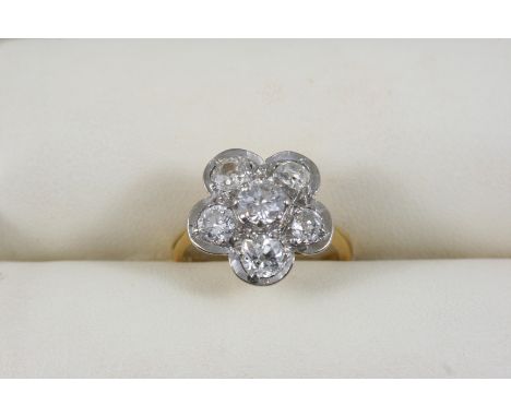 A DIAMOND CLUSTER RING centred with an old brilliant-cut diamond within a surround of five cushion-shaped diamonds, weighing 