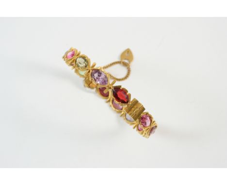 A SPINEL AND GOLD HALF HINGED BANGLE set with oval-shaped multi coloured spinels, in gold.