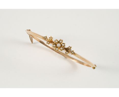 A VICTORIAN GOLD AND PEARL SET HALF HINGED BANGLE the floral design set with graduated small pearls. With box.