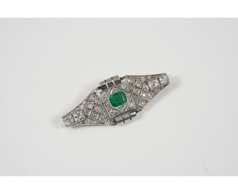 AN ART DECO EMERALD AND DIAMOND BROOCH the central emerald is set within a surround of graduated circular-cut diamonds, 4.5cm