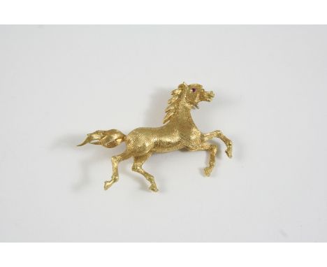 AN 18CT. GOLD HORSE BROOCH realistically formed, with ruby eye, 5cm. wide, 10.8 grams.