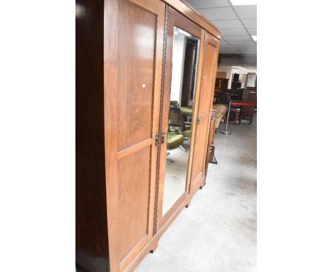 An early 20th Century mahogany triple wardrobe having central mirror door, width approx. 199cm