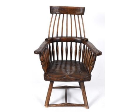 A Windsor style stick back kitchen armchair, the elm seat approx. 7.5 cm deep, on chamfered legs joined by a H stretcher  See