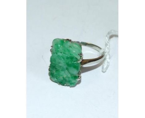 A white coloured metal ring, set a carved and pierced jade panel