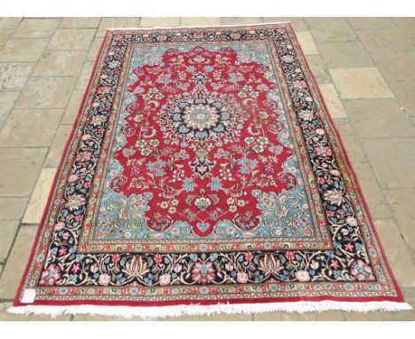 An Eastern medallion carpet, decorated stylised floral motifs on a red ground, 294 x 202 cm 