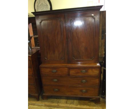 A mahogany cabinet on chest, the moulded and dentil cornice above a pair of panel doors enclosing shelves, the base the with 