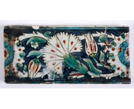 An Iznik pottery tile, decorated stylised flowers, probably 16th century (a.f.) 25.5 x 12 cm  See illustration