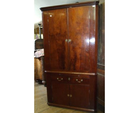 A 19th century mahogany floor standing corner cupboard, the moulded and dentil cornice above a pair of panel doors, the base 