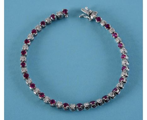 An 18ct white gold, ruby and diamond line bracelet  See inside back cover colour illustration