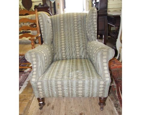 A Victorian upholstered button back armchair, on turned front legs, and an upholstered wing armchair, on turned front legs (2
