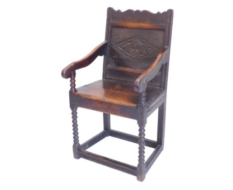 An oak Wainscote chair, the panelled back carved with lozenge, with shaped arms, solid seat, on bobbin turned supports with p