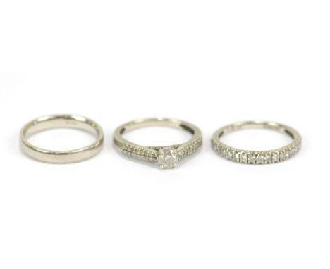 A platinum and diamond solitaire ring, size I1/2, a platinum and diamond half eternity ring, size J1/2, and a platinum weddin