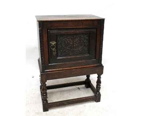 A 17th century and later oak cabinet, with carved central door enclosing a shelf, the base raised on ring turn stretchered su