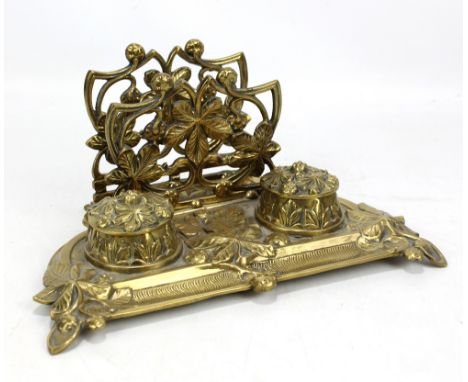 A brass foliate motif desk stand, the twin inkwells with ceramic liners, width 28cm.